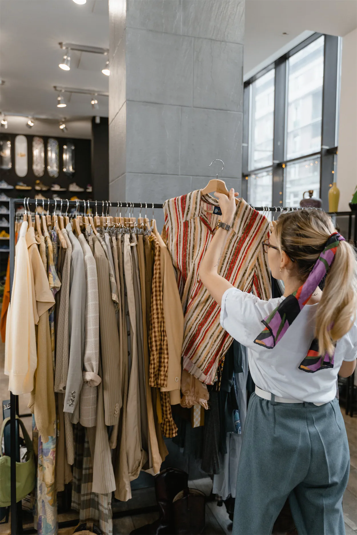 A women pulling a shirt off a clothing rack