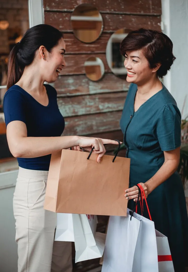 a lady handing a shopping bag to another lady