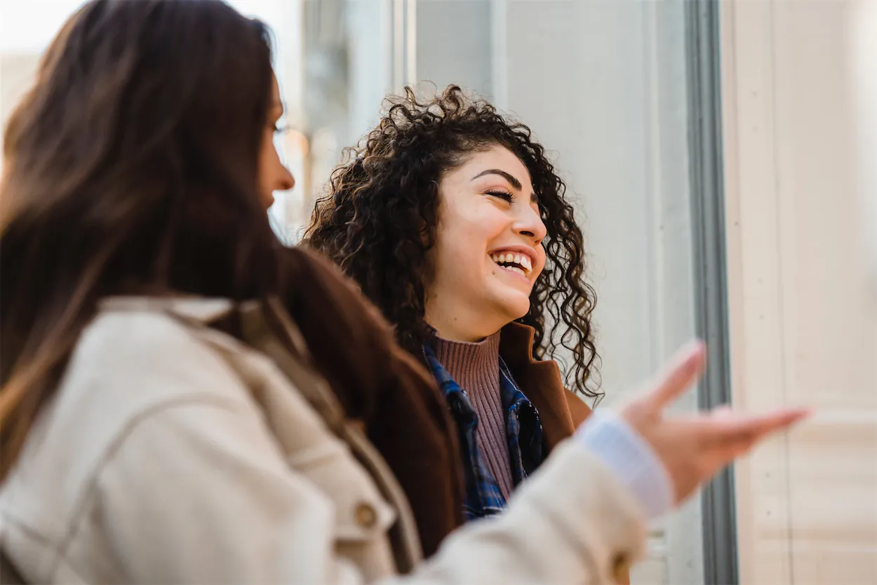two women smiling while talking
