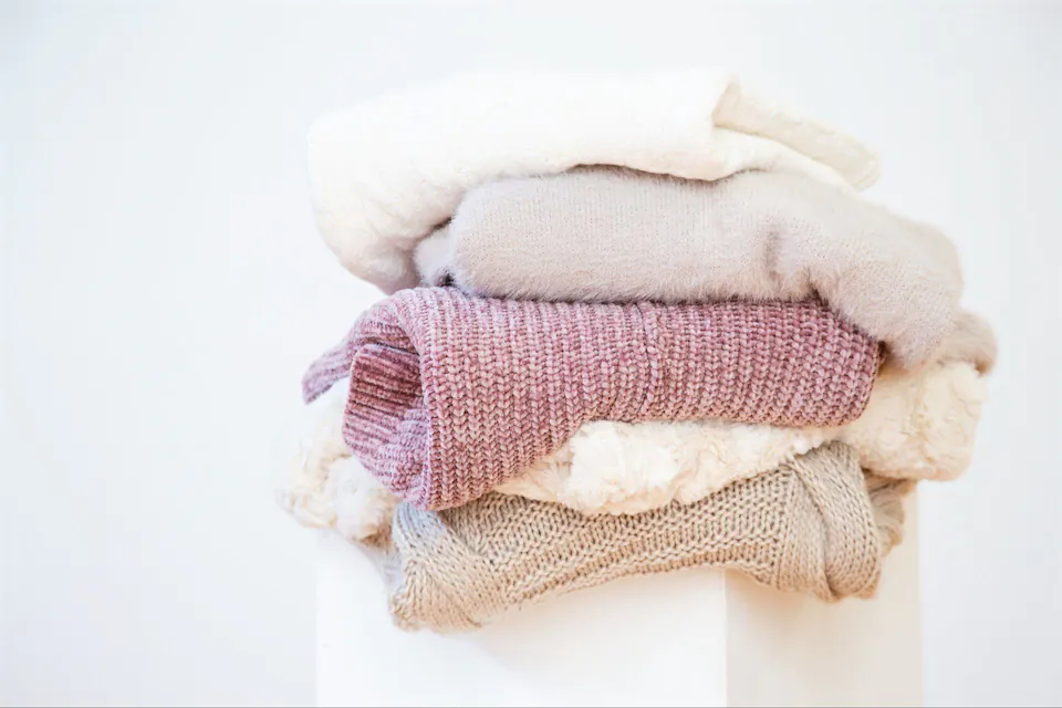 A pile of sweaters on a white box
