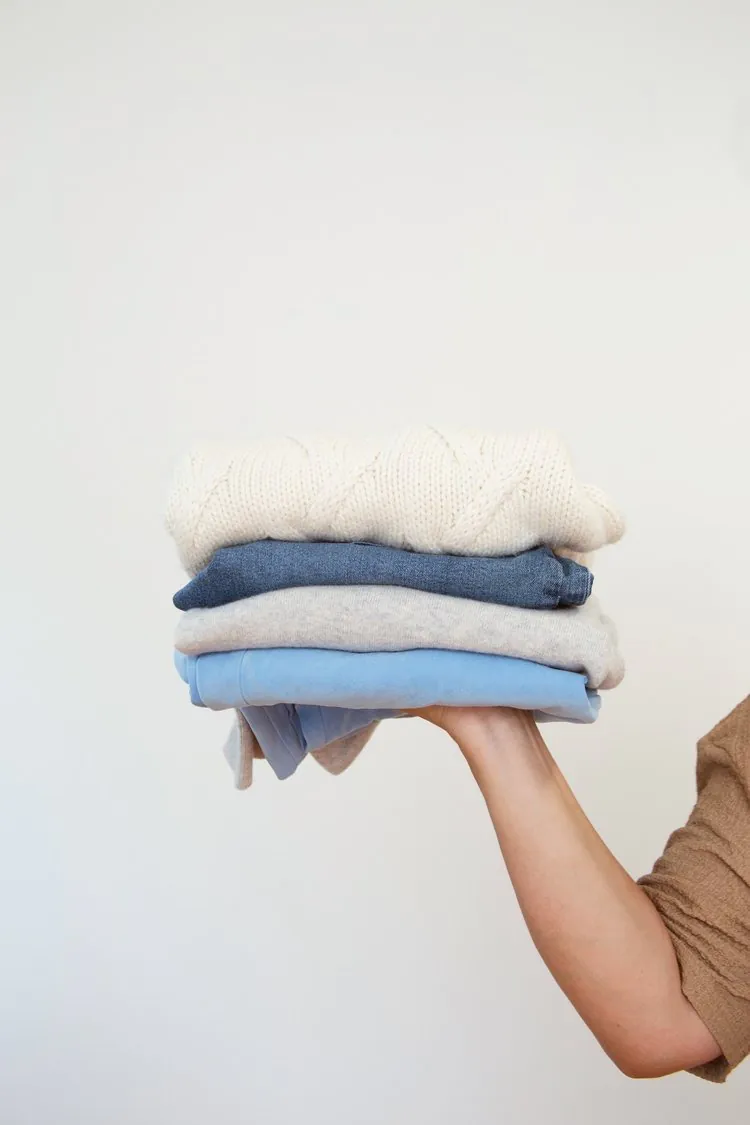 someones arm holding folded clothes